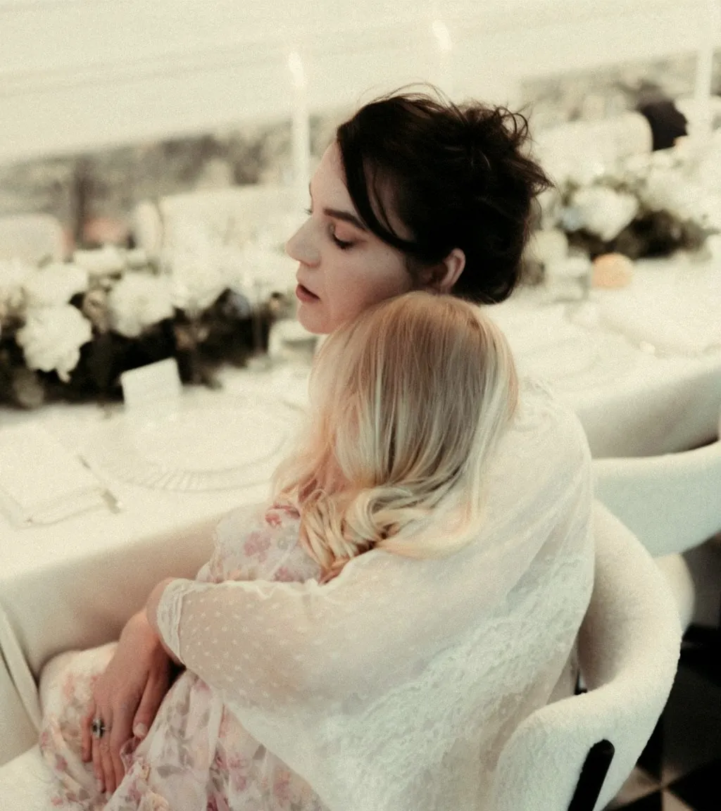 Ilinca holding her daughter close at a table set with white flowers